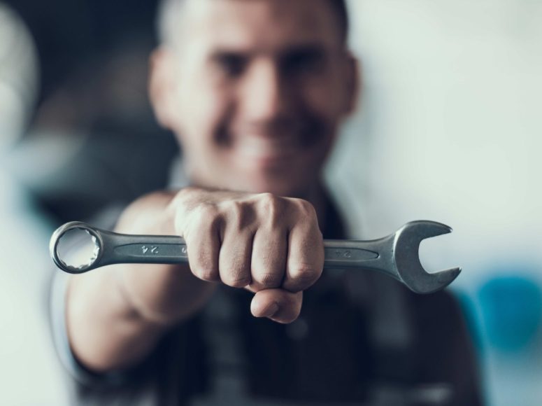 Mechaniker für Reparatur und Wartung bei TOP Markenspezialist Autohaus Machel, Spezialist für Renault und Dacia. Mechaniker schiebt Schraubenschlüssel vor